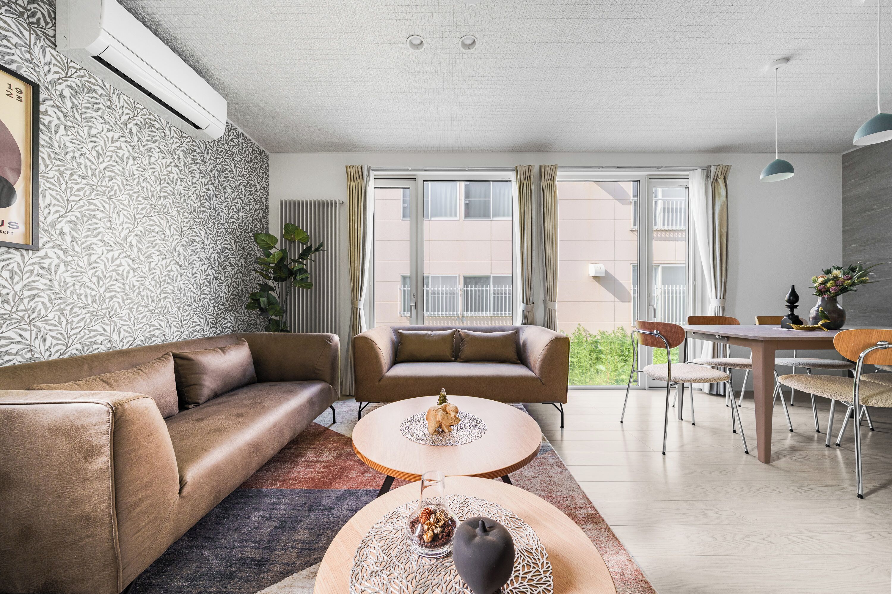A modern living room with a sofa, a coffee table, and a dining area with chairs and a table.