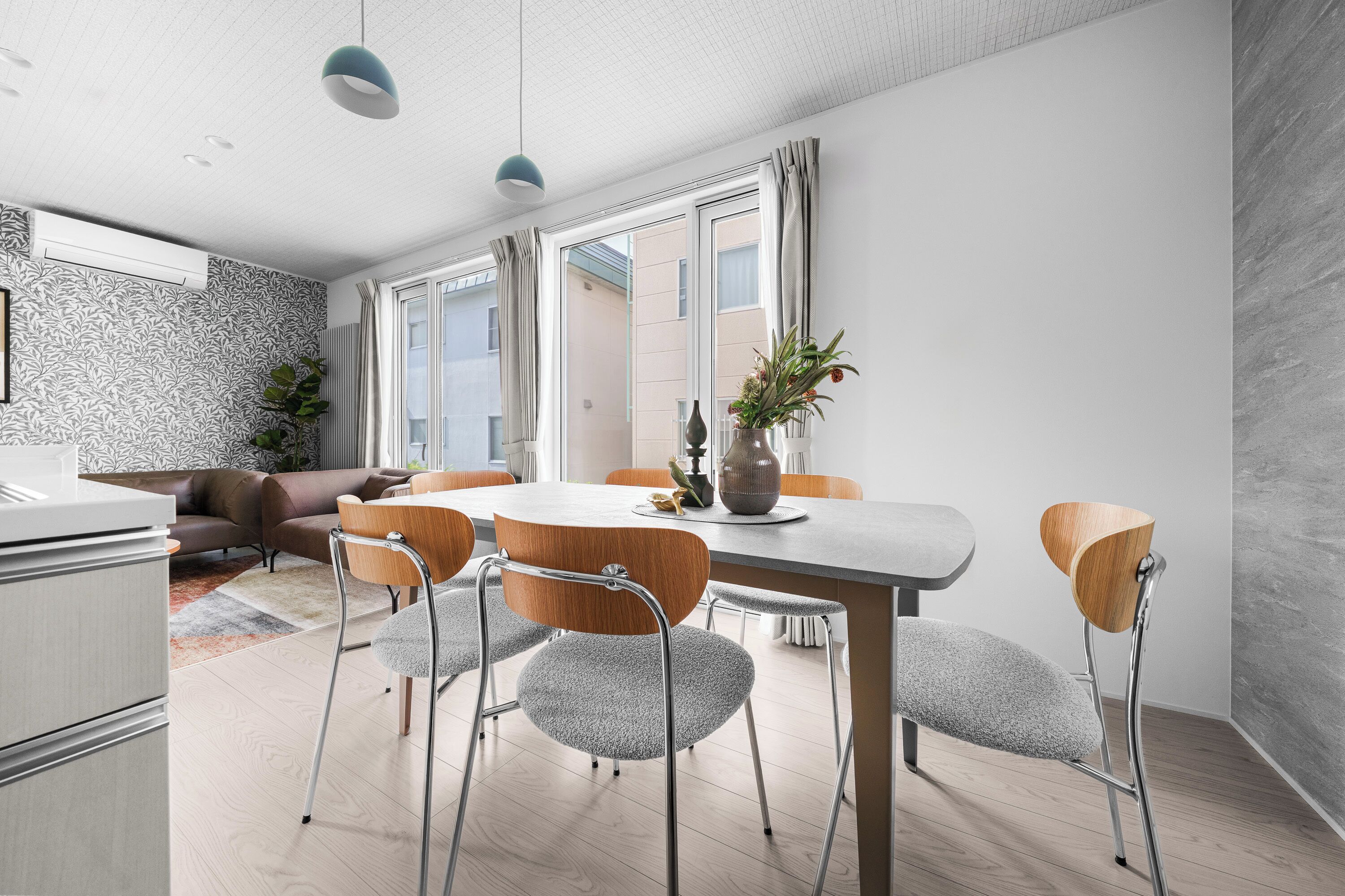 A modern dining area with a round table, chairs, and a vase with flowers.