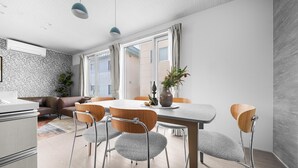 Un comedor moderno con una mesa redonda, sillas y un florero con flores.