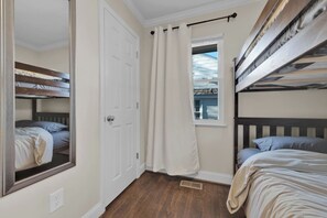 A bedroom with bunk beds, a window with curtains, a door, and a mirror. - The Scandic - Modern Group Stay/Fully Fenced Yard (Birmingham)
