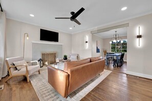 Un salon moderne comprenant un canapé, un fauteuil, une cheminée et un coin repas avec une table et des chaises.