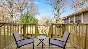 A wooden deck with two chairs and a small table, surrounded by a wooden fence.