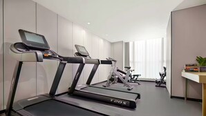 Uma academia moderna com esteiras, bicicletas ergométricas e um remo.