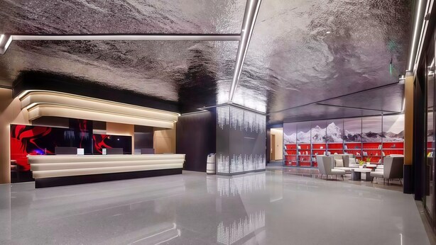 Um lobby moderno com balcão de recepção, área de estar e uma grande estante com vista para as montanhas.