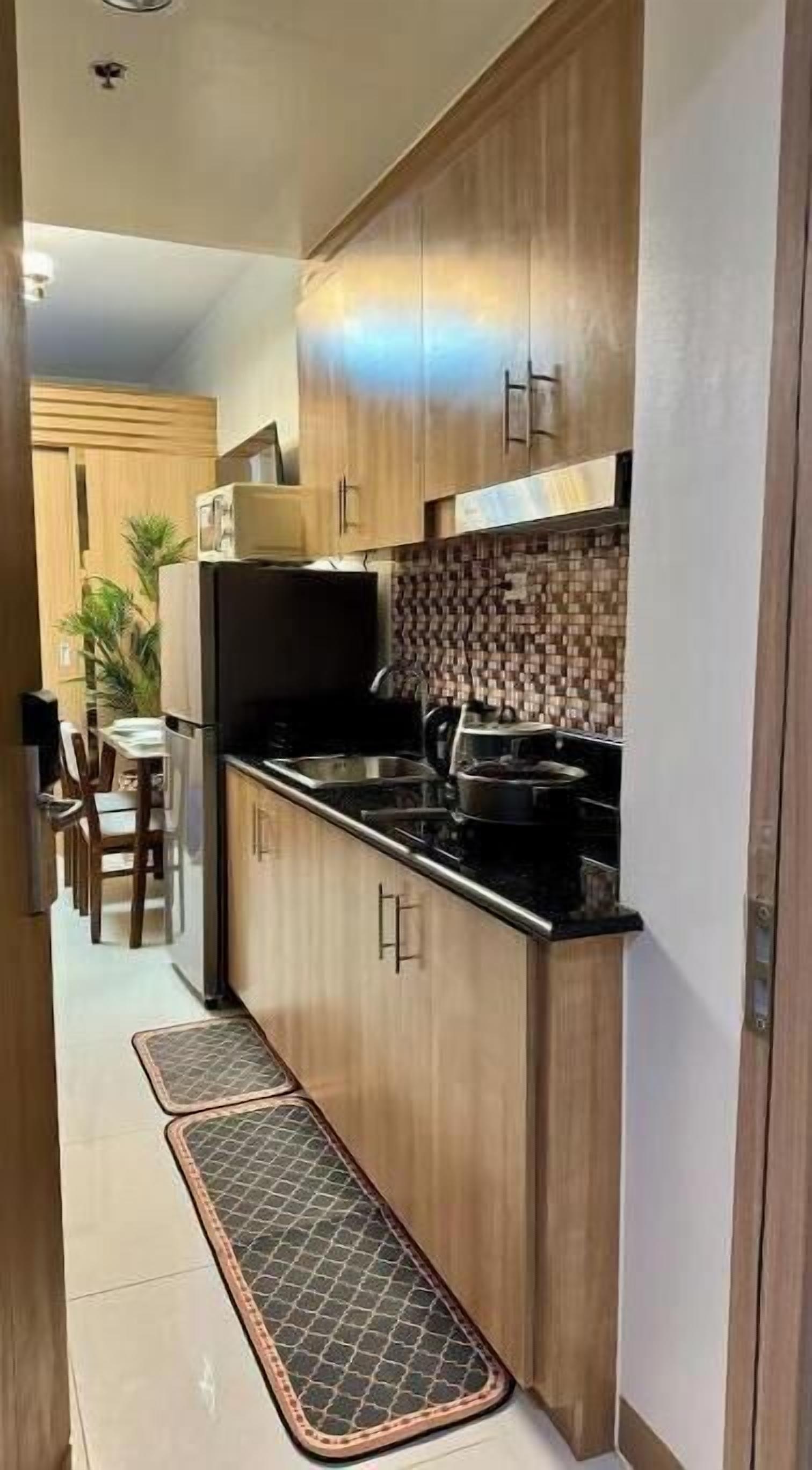 Una cocina con armarios de madera, encimera negra y salpicadero de azulejos.