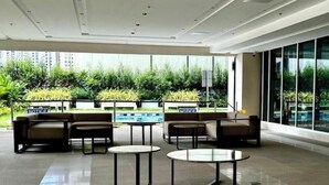 Ein moderner Lounge-Bereich mit Sitzgelegenheiten und Tischen, großen Fenstern und Blick auf Grünflächen.