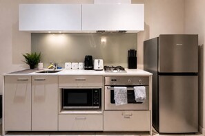 A modern kitchen with a built-in oven, microwave, and a stainless steel refrigerator. - CBD Apartment | Cozy Outdoor Balcony Setup, Heated Pool, Gym, Sauna and Dining (Melbourne)