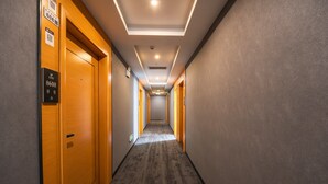 Ein Hotelgang mit Holztüren, Teppichboden und einer Decke mit Einbautenbeleuchtung.