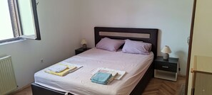 Ein ordentlich gemachtes Bett mit Kissen, einer Nachttischlampe und einem gefalteten Handtuch auf dem Nachttisch.