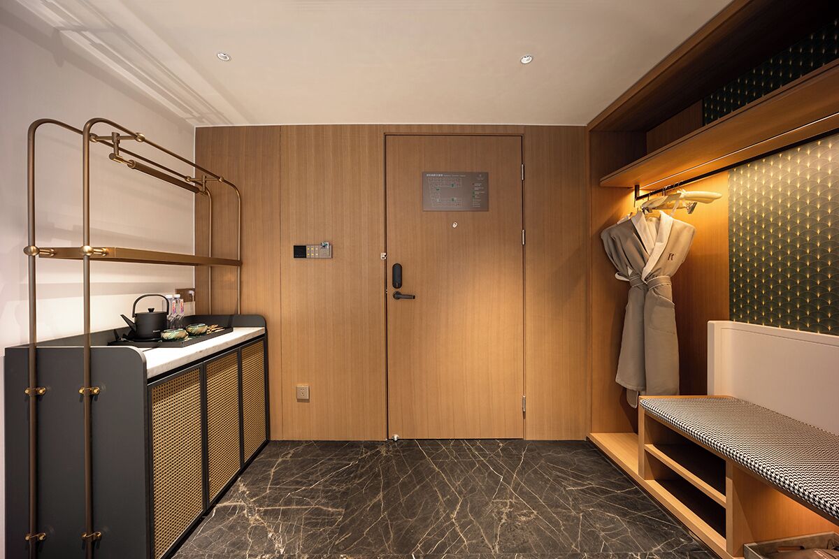 Un baño moderno con puerta de madera, toallero y un banco.