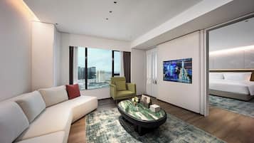 A modern hotel room with a sofa, armchair, and a bed.