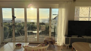 Ett vardagsrum med en balkong, en tv och ett stativ.