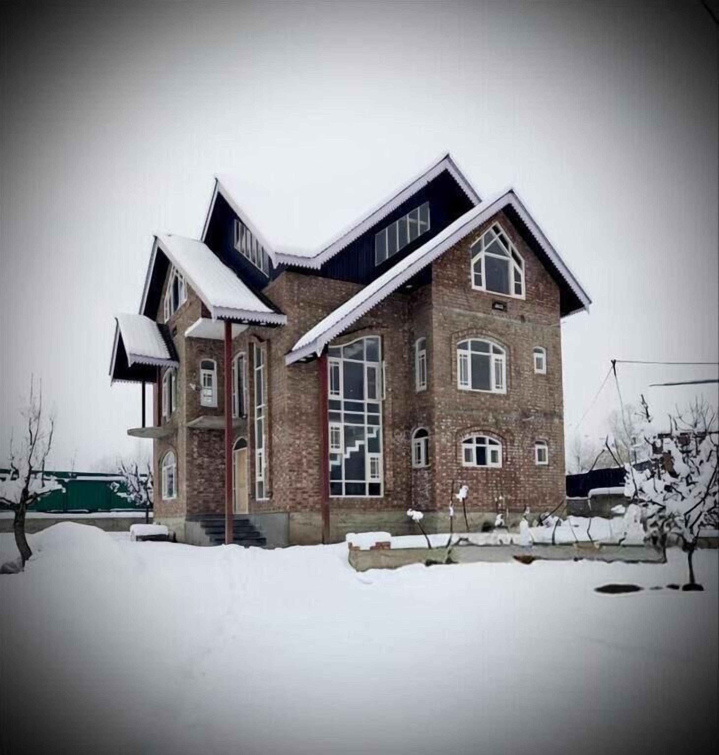 A two-story brick house with a gabled roof and large windows.