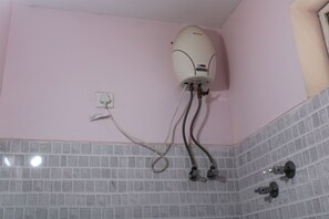 Une salle de bain avec un chauffe-eau blanc fixé au mur, un sol carrelé et un mur blanc.