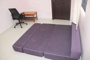 A room with a bed, a chair, a small table, and a door. - Ramana Palace (Tiruvannamalai)
