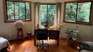 A room with a wooden floor, a desk with a chair, a potted plant, and large windows with curtains. - Unique 2 Story Dome (Rivas)