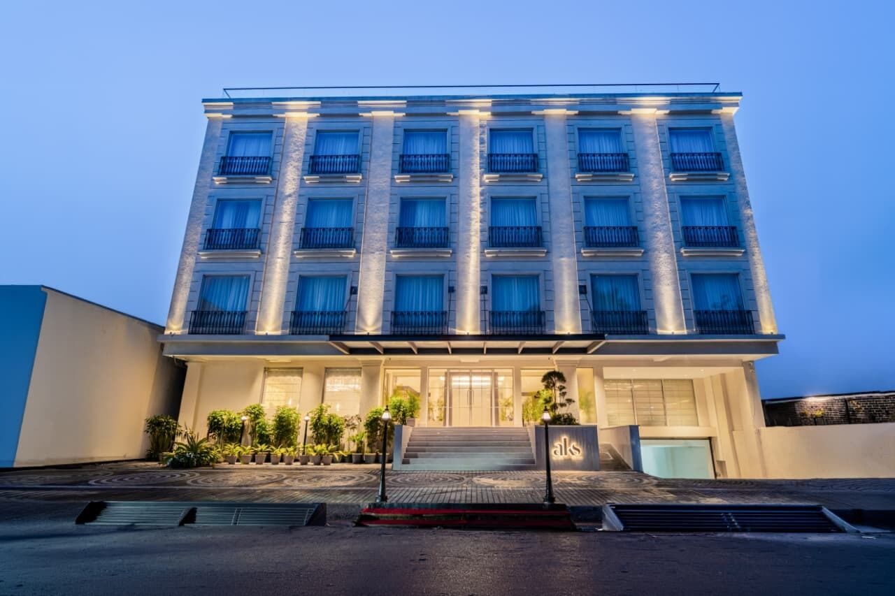 Un hotel de varios pisos con entrada central, balcones y una fachada bien iluminada.