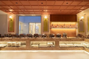 A buffet area with multiple food stations and a view of the outside. - AKS Palace (Varanasi)