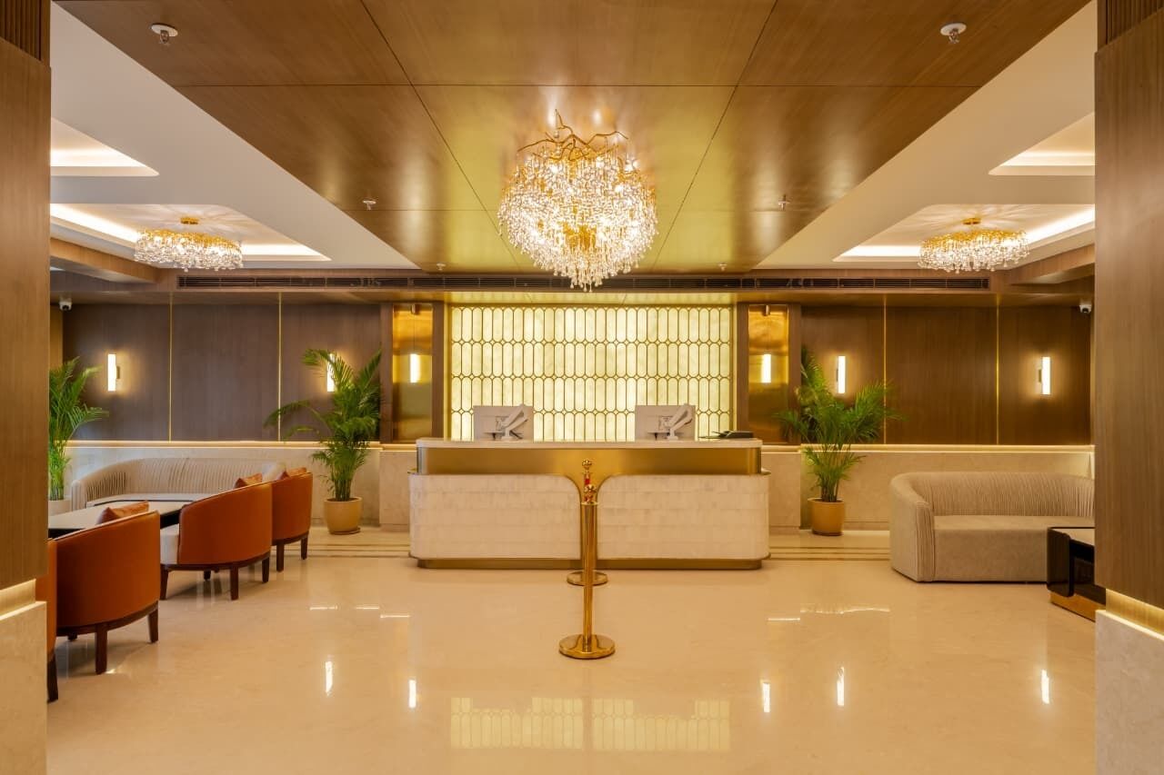 A hotel lobby with a reception desk, seating area, and decorative lighting.