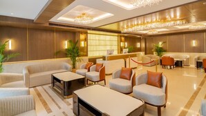 A hotel lobby with sofas, armchairs, a reception desk, and chandeliers. - AKS Palace (Varanasi)