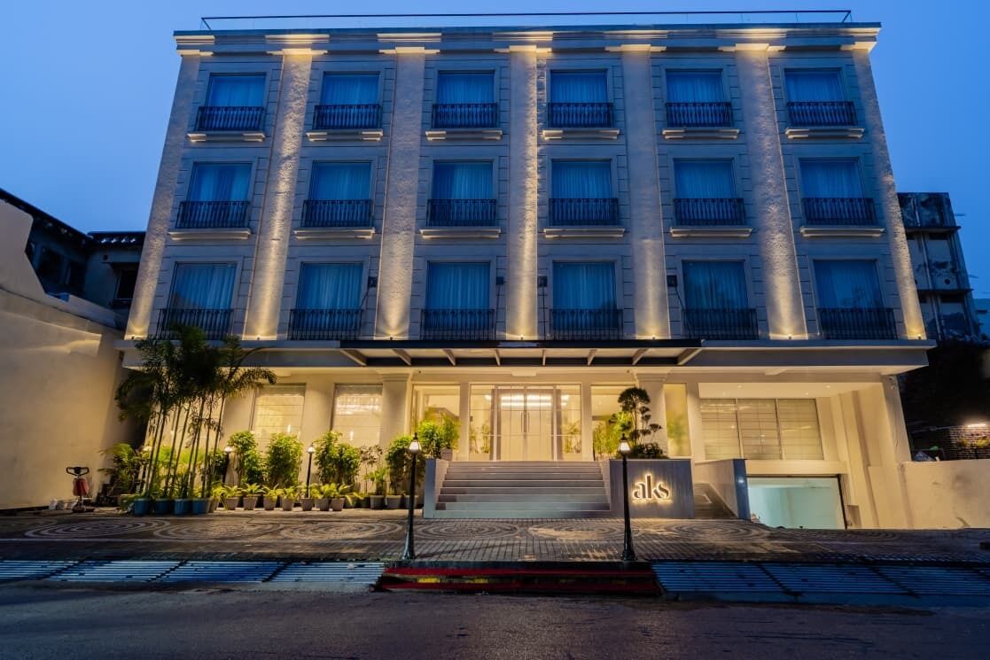 A multi-story hotel with a central entrance, balconies, and a well-lit facade.