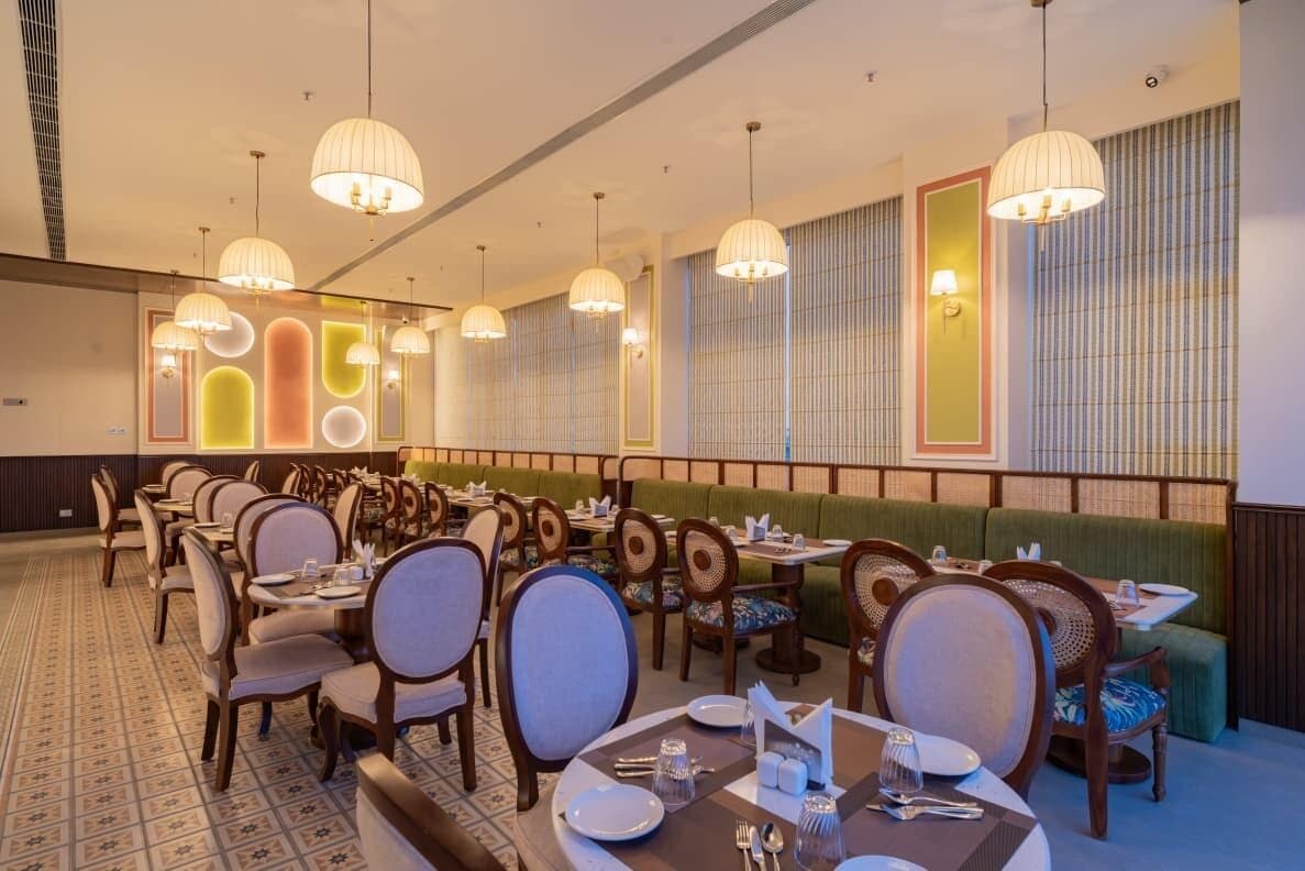 A restaurant with multiple dining tables and chairs, ambient lighting, and a patterned wall design.