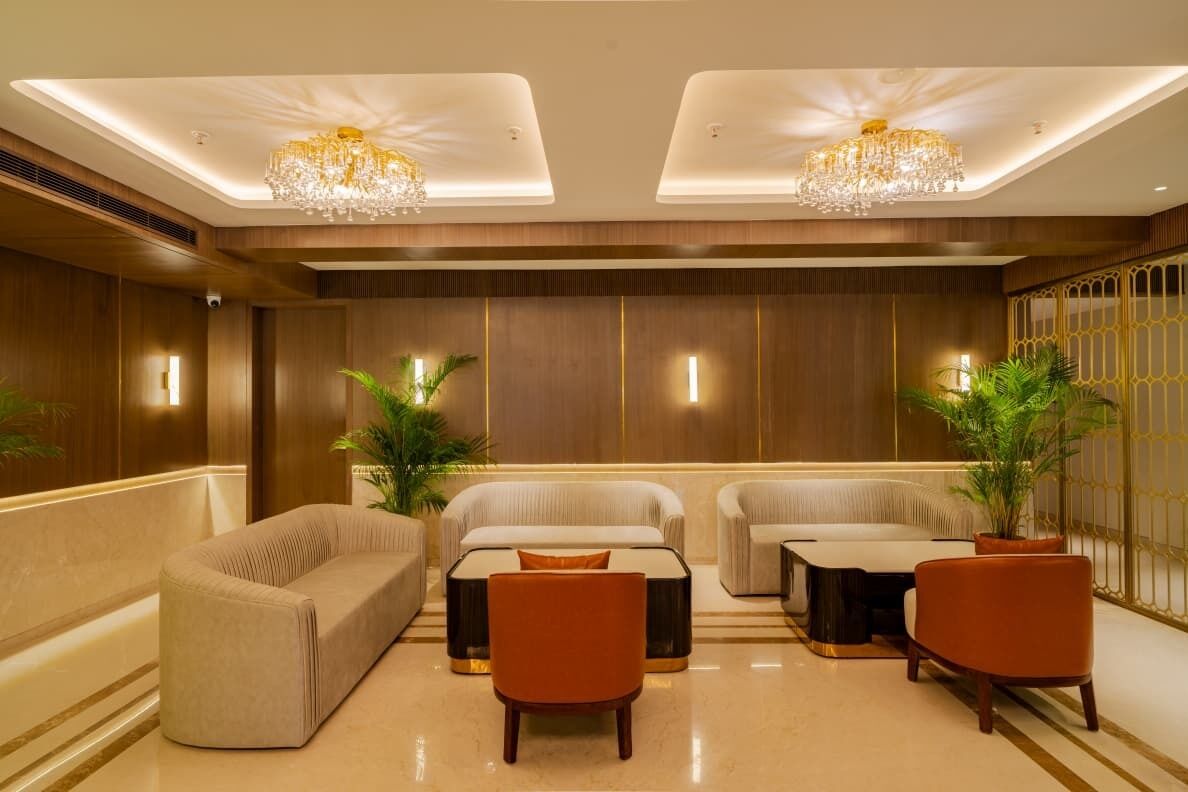 A hotel lobby with a sofa set, two armchairs, a coffee table, and a chandelier.