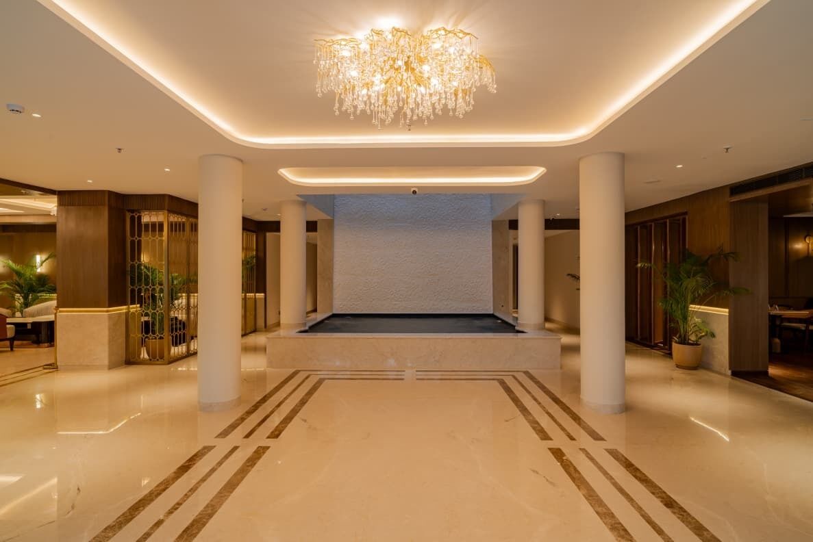 A spacious lobby with a central seating area, columns, and a chandelier.