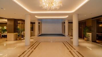 A spacious lobby with a central seating area, columns, and a chandelier.