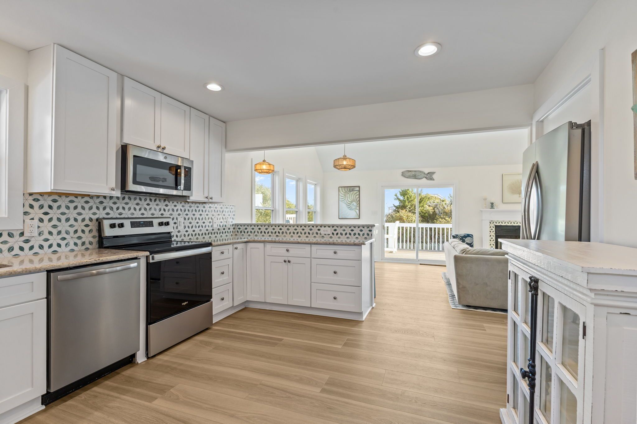 A modern kitchen with white cabinetry, stainless steel appliances, and a patterned backsplash.