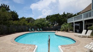Une piscine avec un escalier en métal, entourée d’une terrasse en briques.