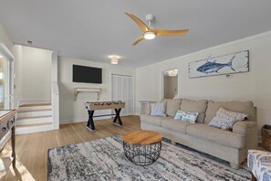 A living room with a sofa, coffee table, and a ceiling fan. - SeaEsta | Private Pool + 5 Min Walk to Beach (Emerald Isle)