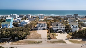 A coastal residential area with houses, a clear view of the ocean, and a road in the foreground. - SeaEsta | Private Pool + 5 Min Walk to Beach (Emerald Isle)