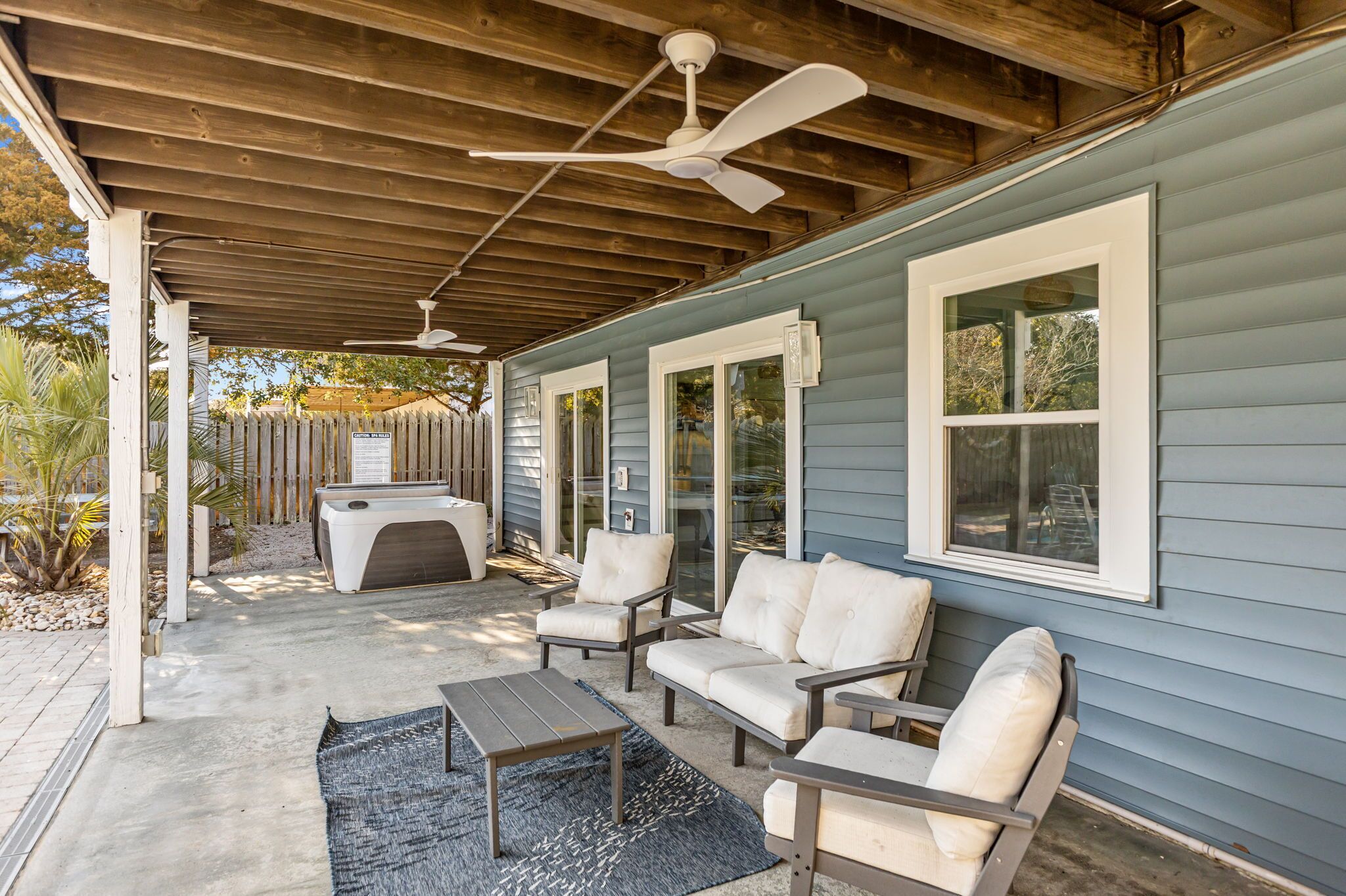 A covered patio with outdoor furniture, a ceiling fan, and a built-in fireplace.