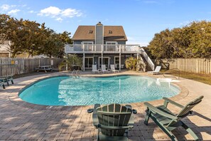 A swimming pool with a wooden deck, lounge chairs, and a house in the background. - SeaEsta | Private Pool + 5 Min Walk to Beach (Emerald Isle)