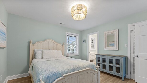 Une chambre à coucher avec un lit, une commode, un miroir et une porte.