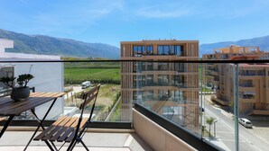 Un apartamento moderno con balcón que da a un paisaje verde y montañas.