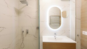 Baño con ducha, lavamanos y espejo.