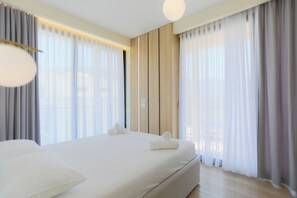 A modern hotel room with a large bed, wooden panel walls, and sheer curtains. - Seaside Serenity Palm Apartment (Orikum)
