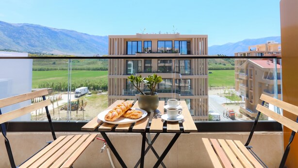 A balcony with a table, a plate of pastries, a potted plant, and cups of coffee. - Modern Pool Side Studio Palm (Orikum)