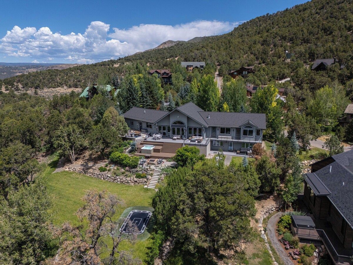 A large house with a spacious backyard, multiple decks, and a swimming pool.