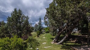 A pathway through a wooded area with a stone bench and a pergola.