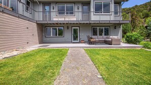 A two-story house with a covered patio, a gravel pathway, and a grassy lawn.