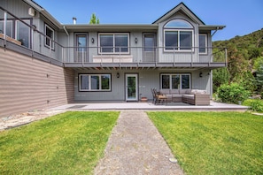 A two-story house with a covered patio, a gravel pathway, and a grassy lawn.