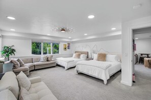 A modern bedroom with a sofa, two beds, and a large window.
