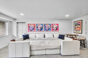 A bedroom with a large bed, a small table, and a framed artwork on the wall.