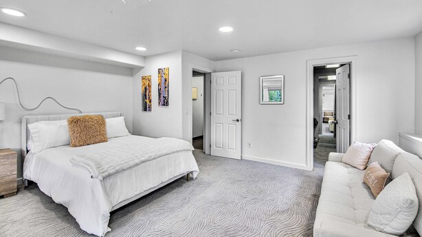 A modern bedroom with a large bed, a sofa, and a unique ceiling light fixture.