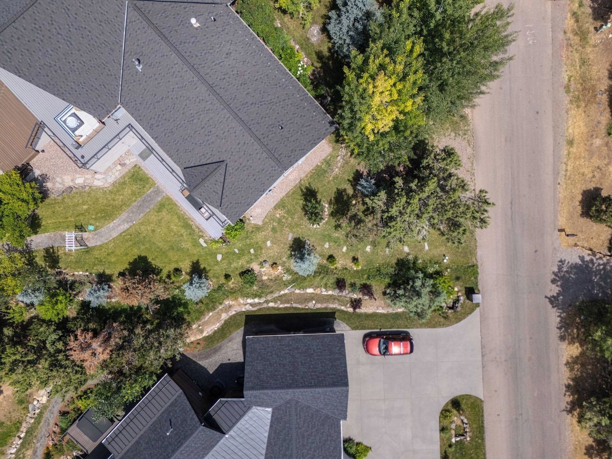 An aerial view of a residential area with a house, a driveway, and a red car parked on the street.