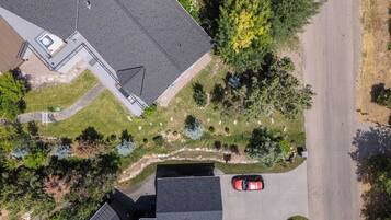 An aerial view of a residential area with a house, a driveway, and a red car parked on the street.