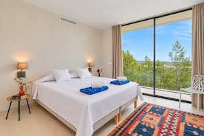 A hotel room with a large bed, two bedside lamps, a view of the outdoors, and a patterned rug. - Casa de Romero 6 pax - Javea, Costa Blanca (Javea)